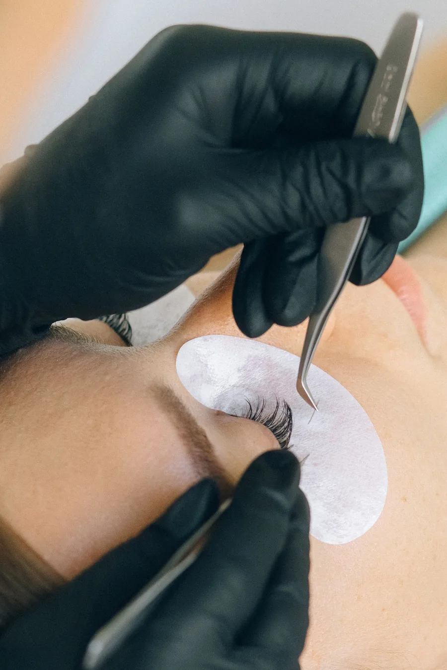 Close detail of an extension being placed on a single isolated natural lash